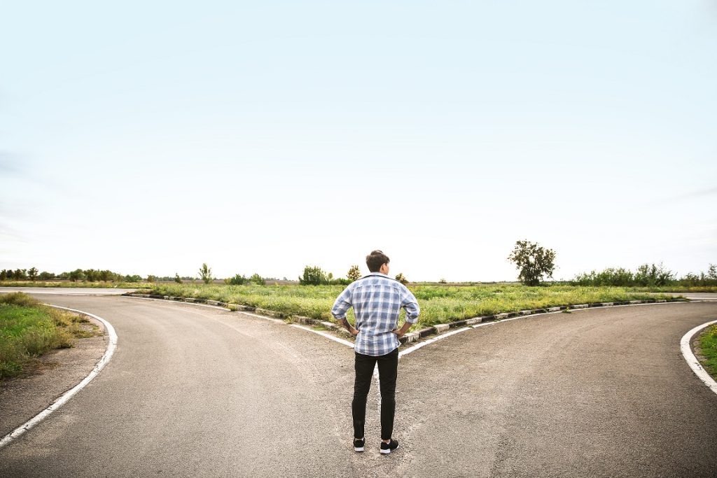 man standing at fork in the road